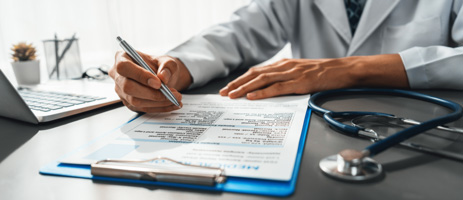 Manos de un médico escribiendo un reporte